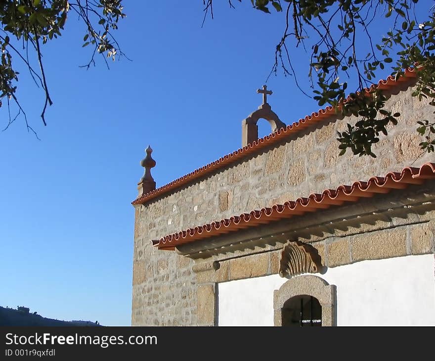 Stone chapel, with visible cross against a blue sky.