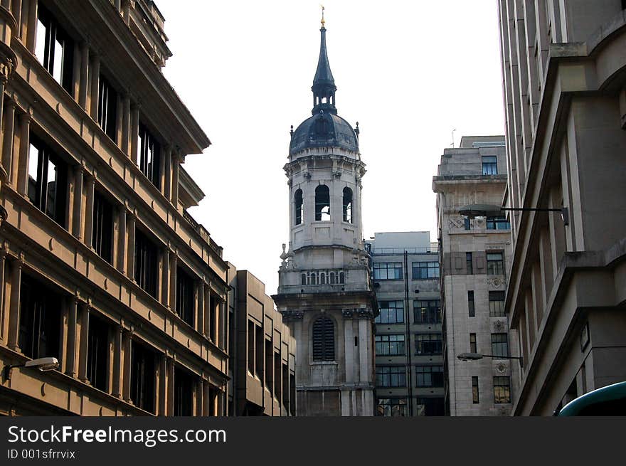 This is an image of a bell tower, in the midst of city buildings. This is an image of a bell tower, in the midst of city buildings.