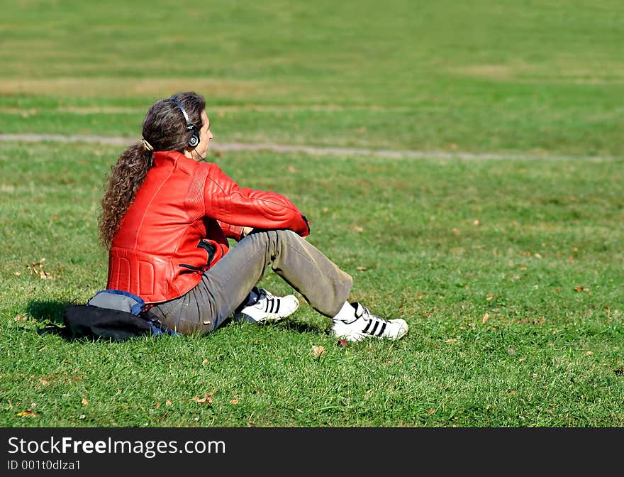 The guy has a rest on a grass and listens to music. The guy has a rest on a grass and listens to music