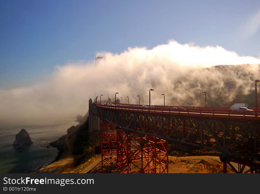 Sunlit fog flowing over the Golden Gate Bridge in the late afternoon.