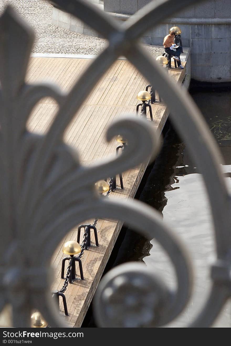 The man reads and sunbathes on quay. The man reads and sunbathes on quay