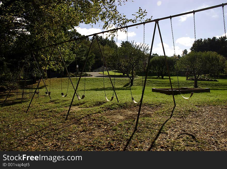 Huge playground swingset situated on beautiful rolling green hillside