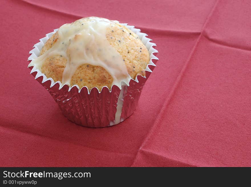 A muffin on a red cloth, still in individual metal baking tin. A muffin on a red cloth, still in individual metal baking tin