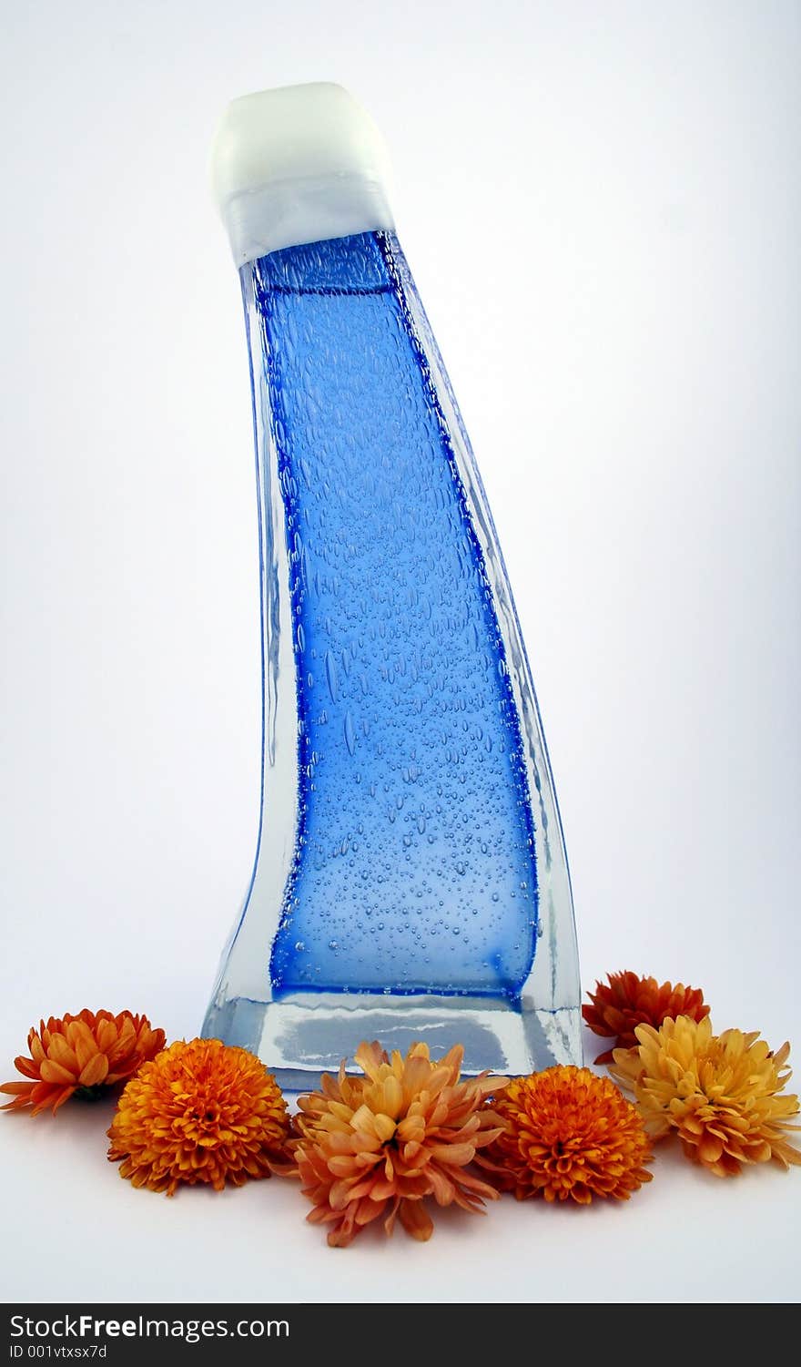 A blue bottle surrounded by orange mums