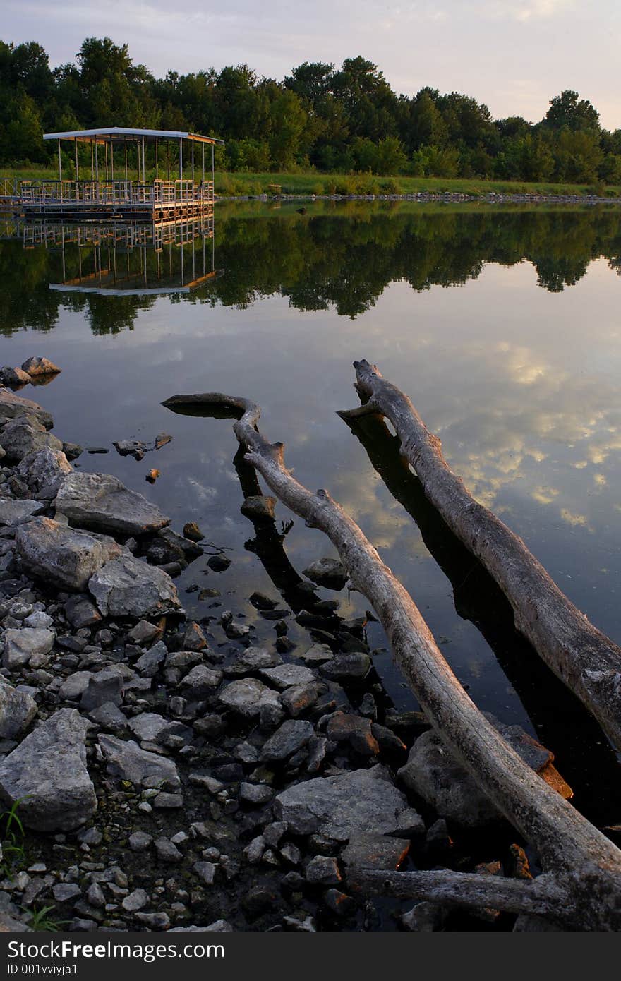 A boat dock on a calm lake at dusk. A boat dock on a calm lake at dusk.