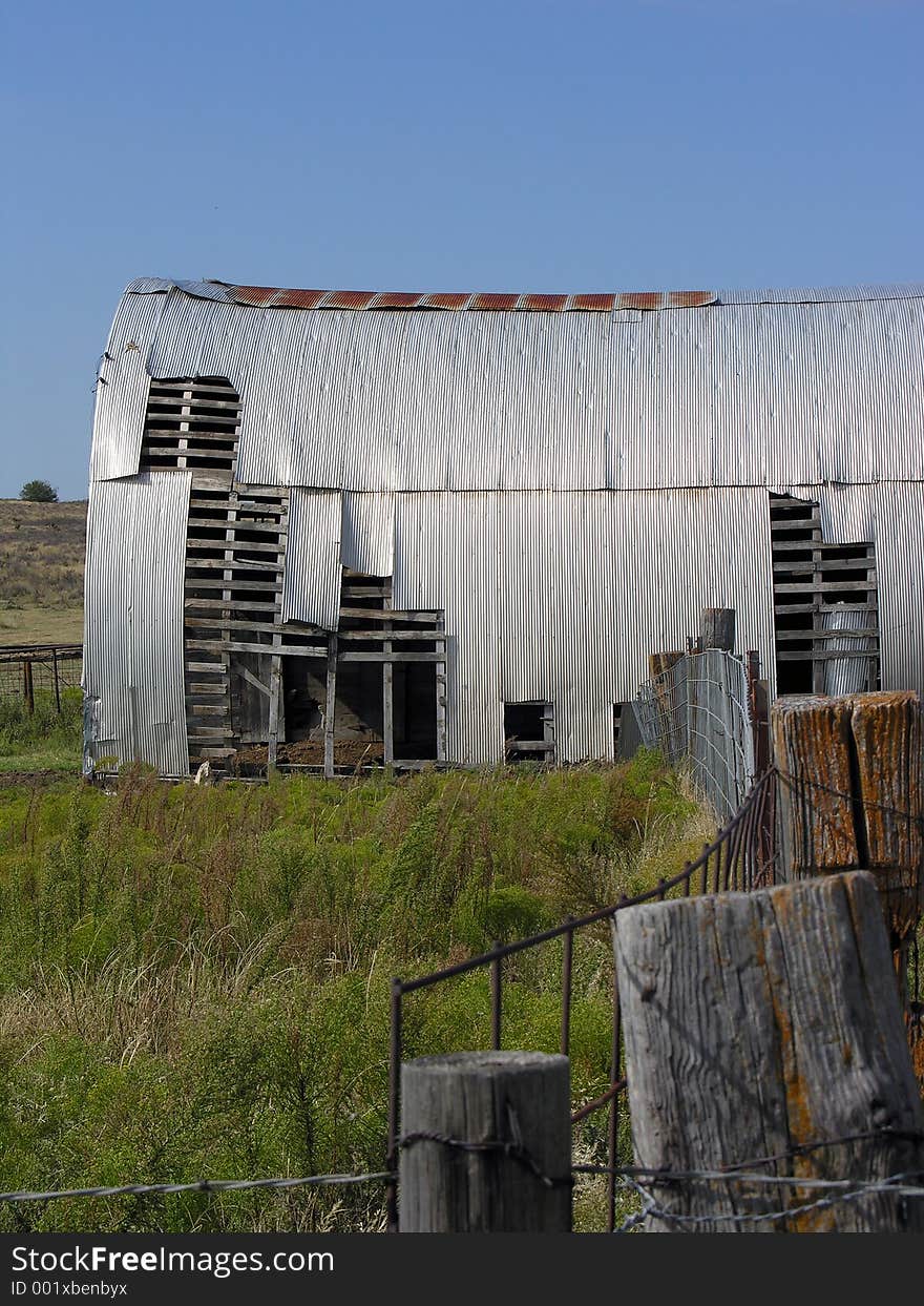 Corrugated tin panels peel from the sides of a quanset barn in northwestern Oklahoma. Corrugated tin panels peel from the sides of a quanset barn in northwestern Oklahoma.