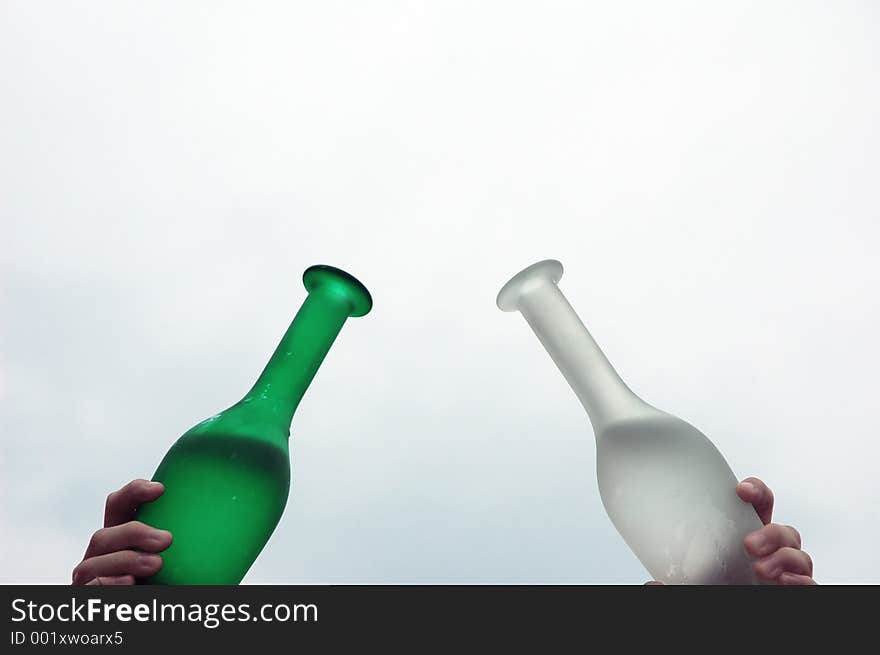 Two glass bottles, one green one white with water inside