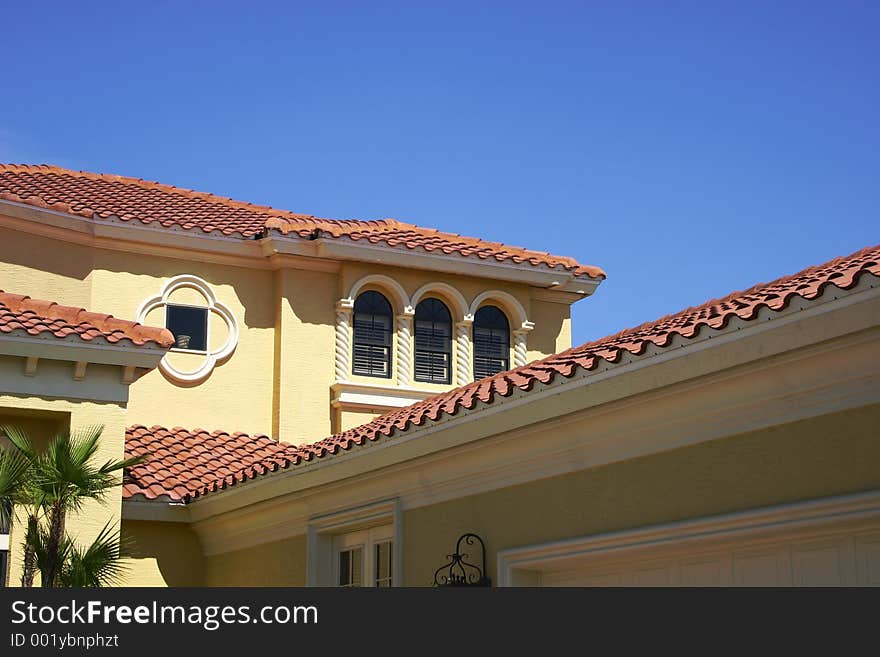 Various angles and levels of tiled roofs against a bright blue sky. Various angles and levels of tiled roofs against a bright blue sky