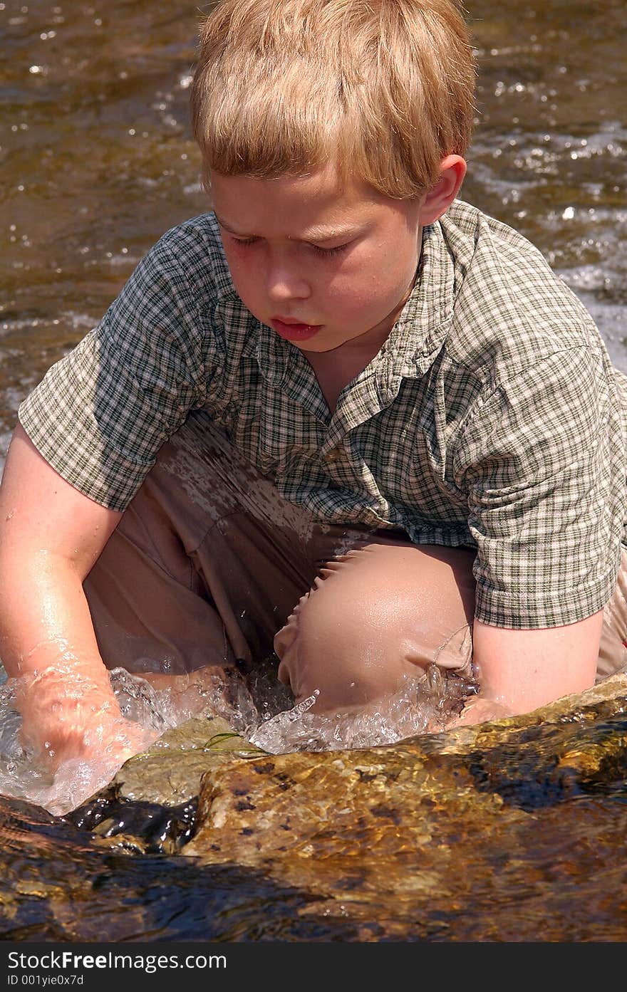 Boy staying cool in a creek on a hot summer day. Boy staying cool in a creek on a hot summer day