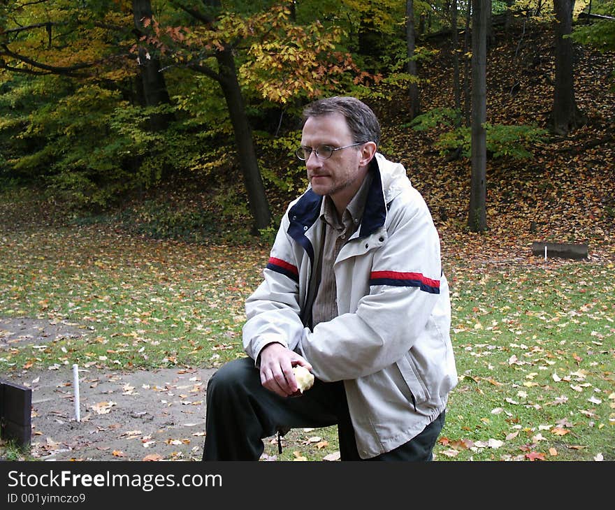 Man with apple in autumn setting, contemplating the scene. Man with apple in autumn setting, contemplating the scene