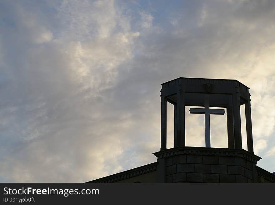 A Christian cross on top of a church with the afternoon sky behind it. A Christian cross on top of a church with the afternoon sky behind it.