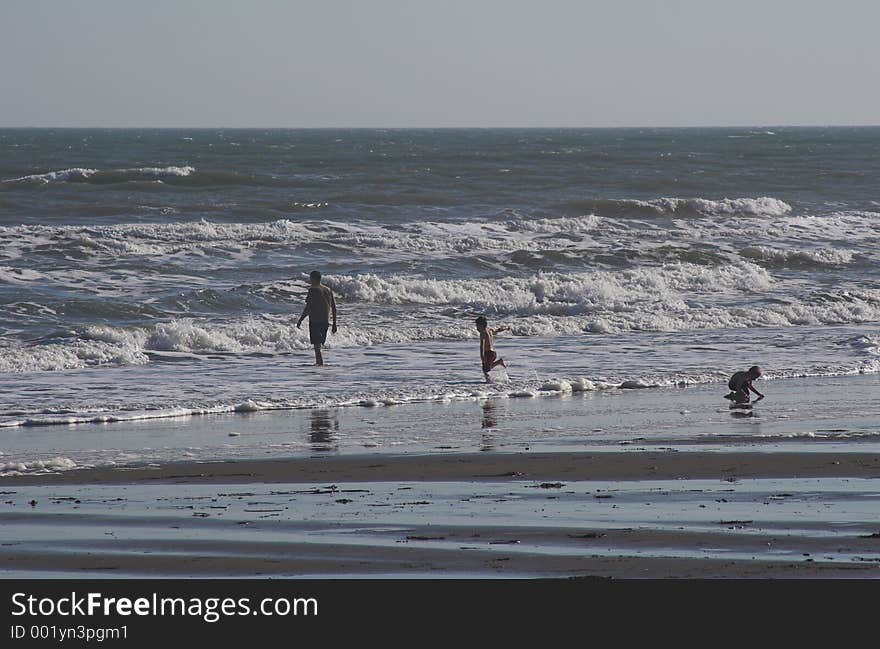 Father & two children playing on the beach and in the surf. Father & two children playing on the beach and in the surf