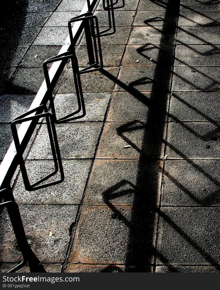 Bike stand in strong sunlight, regularity in shadow on pavement. Bike stand in strong sunlight, regularity in shadow on pavement