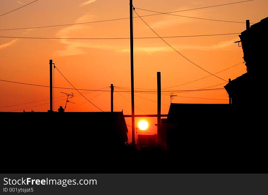 Sunset in residential area with silhouettes of houses and telephone poles and lines. Sunset in residential area with silhouettes of houses and telephone poles and lines