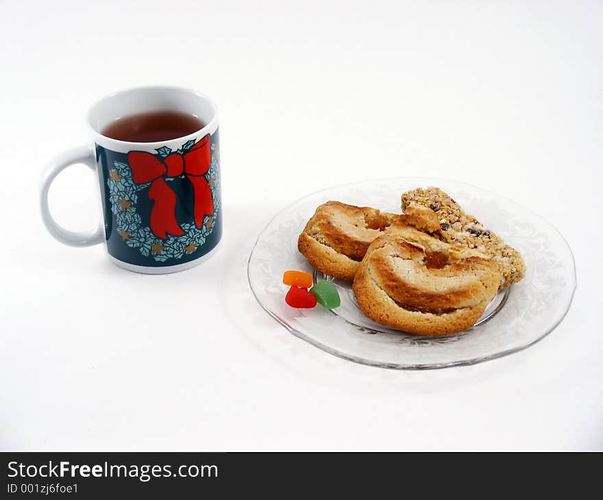 Herbal tea in a Christmas-style mug with assorted snacks on a glass plate. Herbal tea in a Christmas-style mug with assorted snacks on a glass plate