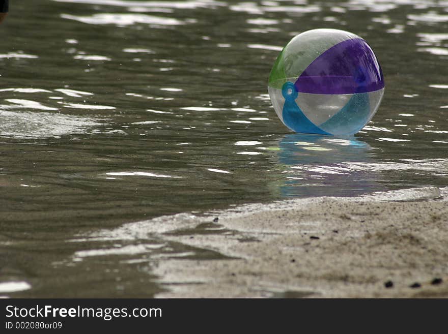 Beach ball floating along waters edge