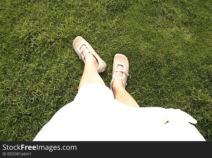 Looking down at my white skirt and cream shoes with bright green grass all around. Looking down at my white skirt and cream shoes with bright green grass all around