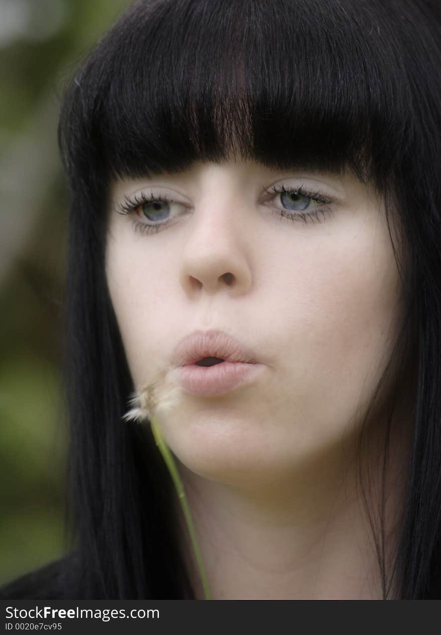 Photo of a young teenage girl blowing the seeds from a dandelion in spring. Photo of a young teenage girl blowing the seeds from a dandelion in spring