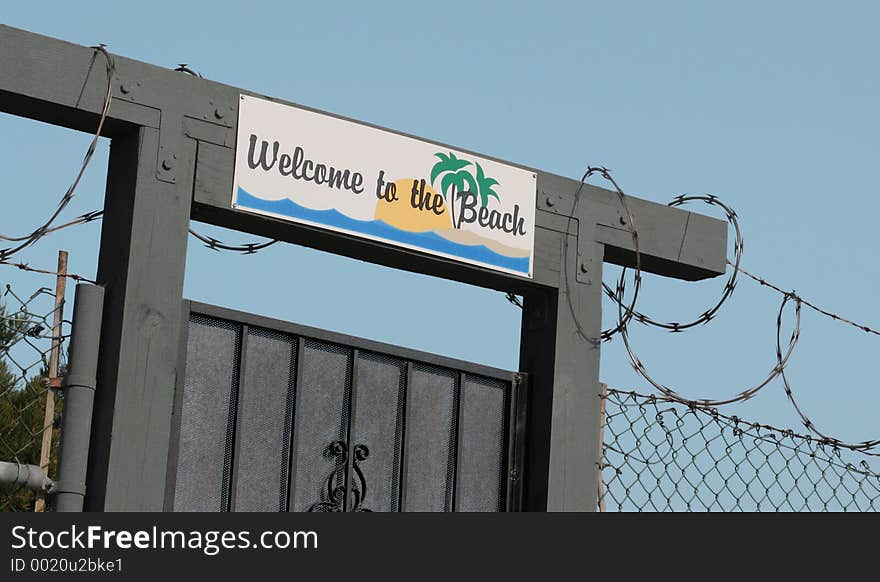 Sign Over entrance To Beach Has Iron gate And Razor wire. Sign Over entrance To Beach Has Iron gate And Razor wire