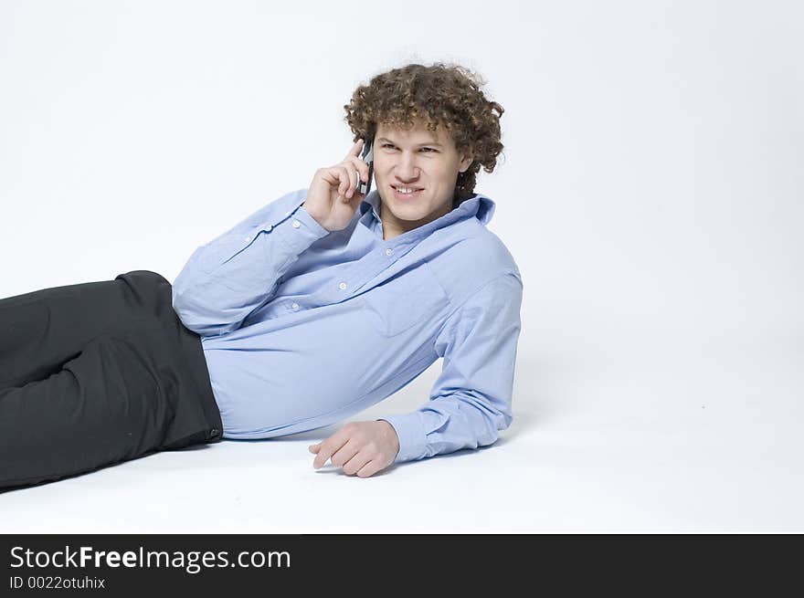 (Boy in relaxed office attire) Boy lying down, leaning up on one arm talking on a cellphone. (Boy in relaxed office attire) Boy lying down, leaning up on one arm talking on a cellphone