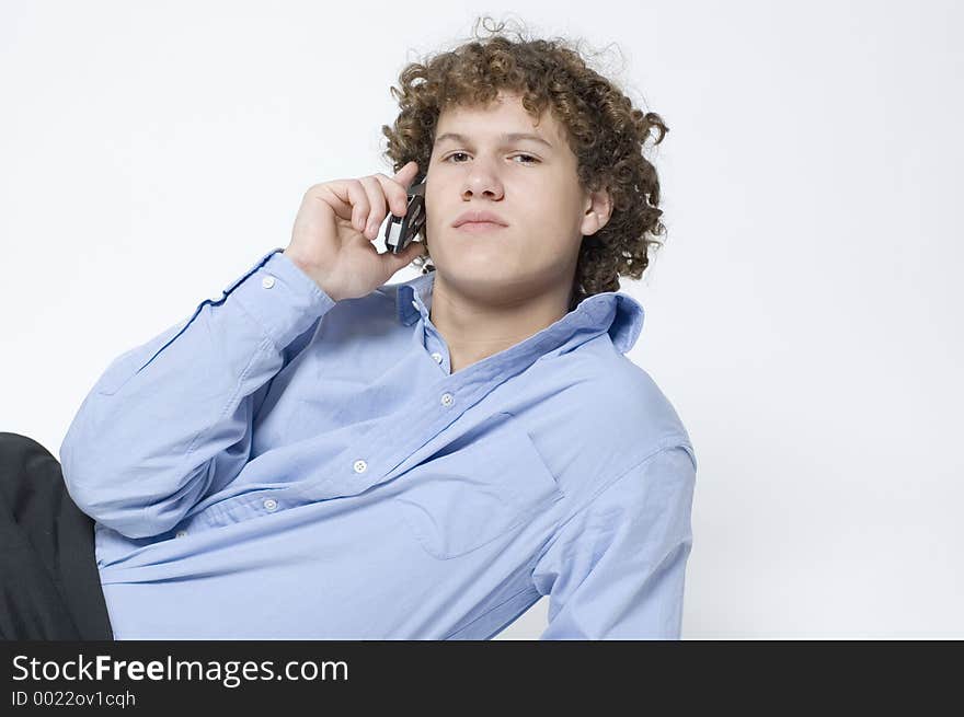 (Boy in relaxed office attire) Boy lying down, leaning up on one arm talking on a cellphone. (Boy in relaxed office attire) Boy lying down, leaning up on one arm talking on a cellphone