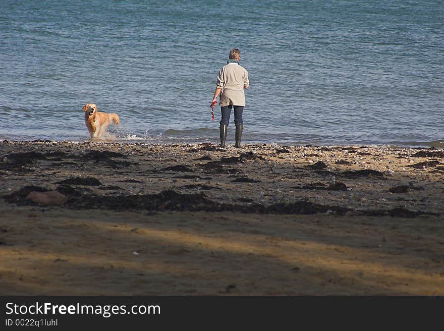 Woman with dog playing in the surf on the seashore. Woman with dog playing in the surf on the seashore