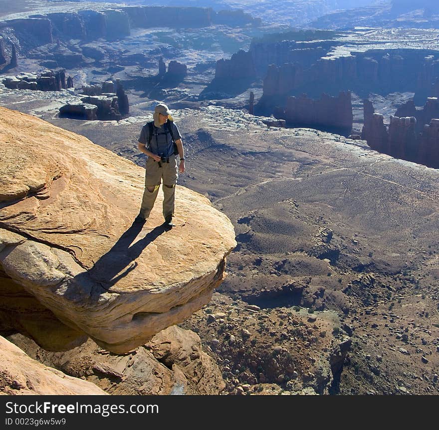 Hiker admires the vista from a risky perch. Hiker admires the vista from a risky perch