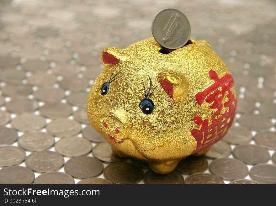 Piggy bank with Chinese prosperity symbol, standing on a floor of coins