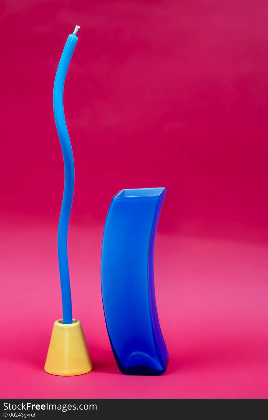 Blue vase and blue candle against dark pink background. Blue vase and blue candle against dark pink background