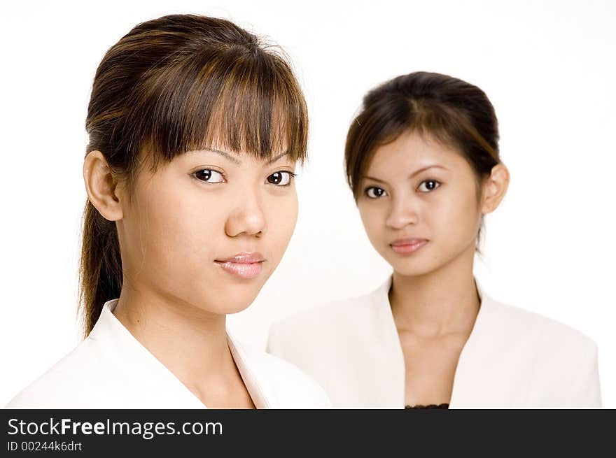 A pair of asian young women in matching business suits. A pair of asian young women in matching business suits