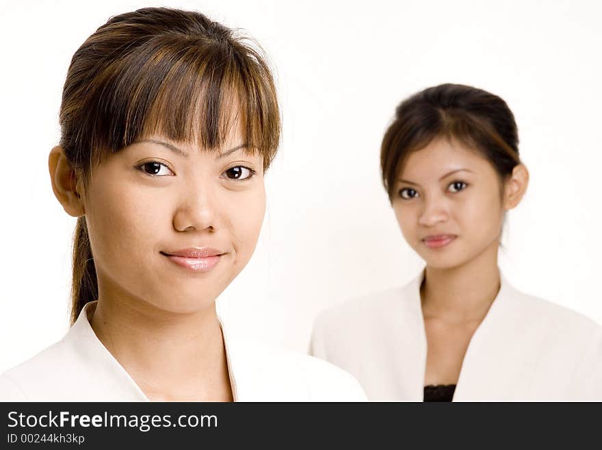 Two smiling asian women in business suits on white background. Two smiling asian women in business suits on white background