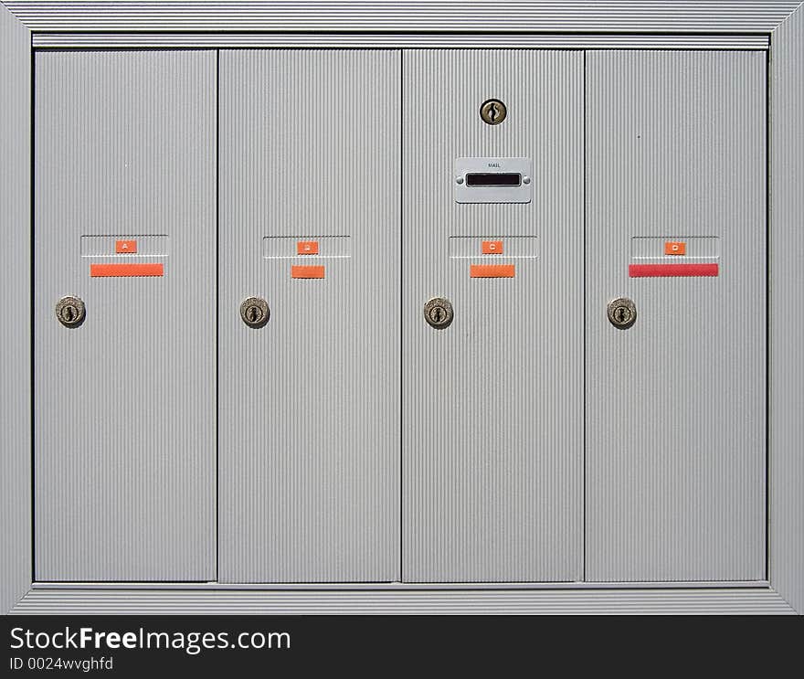 A group of mailboxes doors outside of an apartment building. A group of mailboxes doors outside of an apartment building.