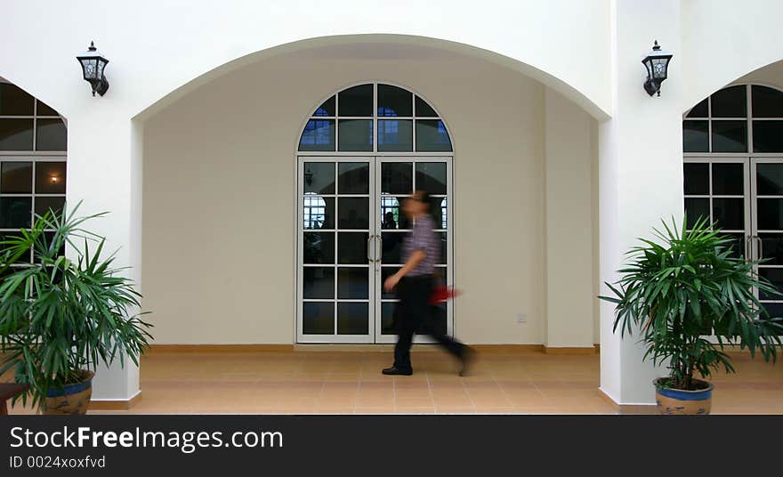 Man walking past modern arches in a church building. Man walking past modern arches in a church building