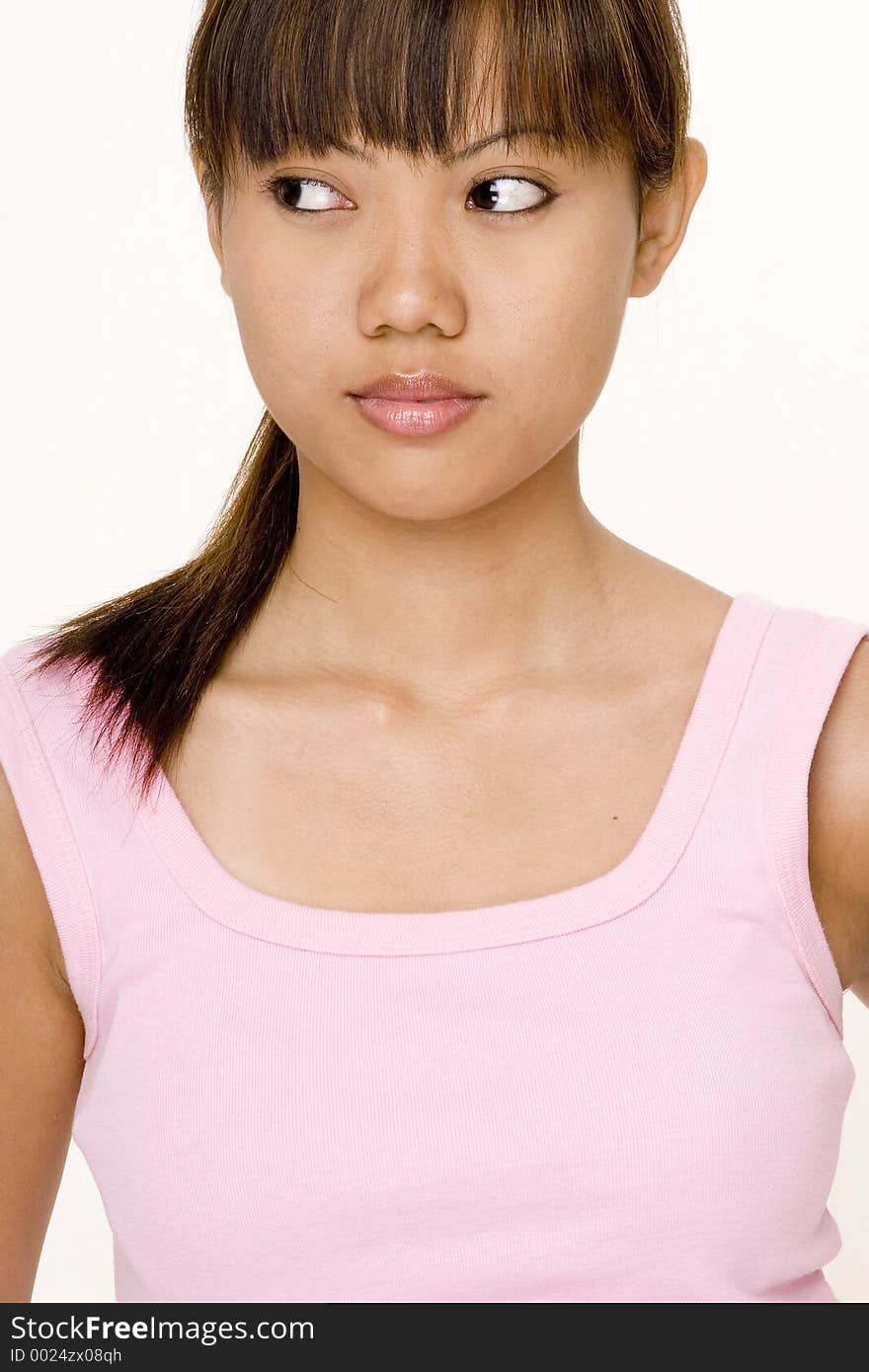 A cute young asian female in a pink top looks to the left. A cute young asian female in a pink top looks to the left