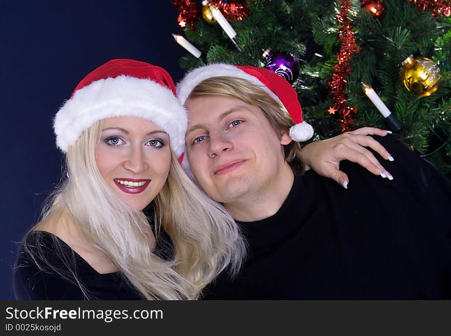 Happy attractive couple in love under christmas tree. Happy attractive couple in love under christmas tree