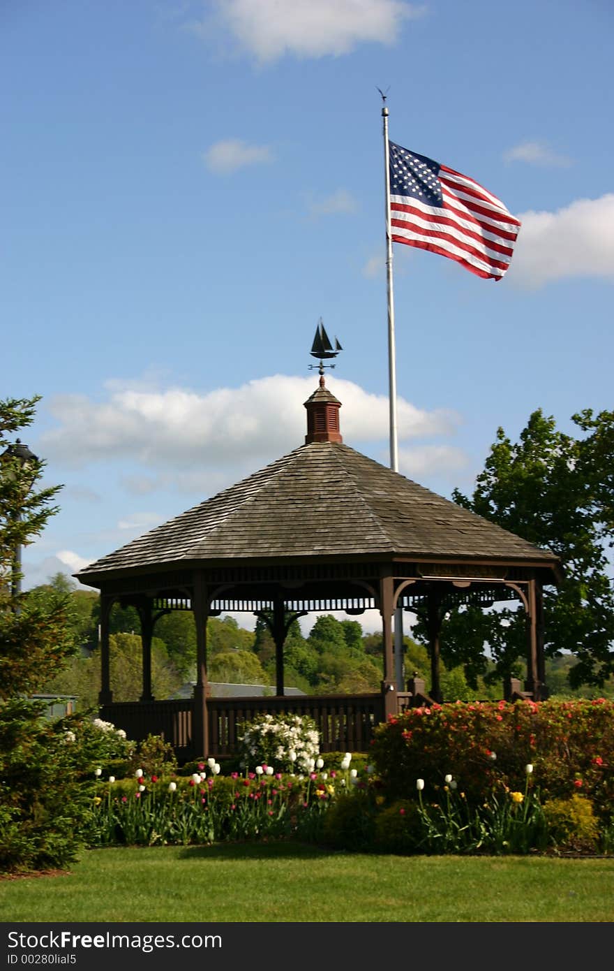 A parks gazebo flying the american flag over it.