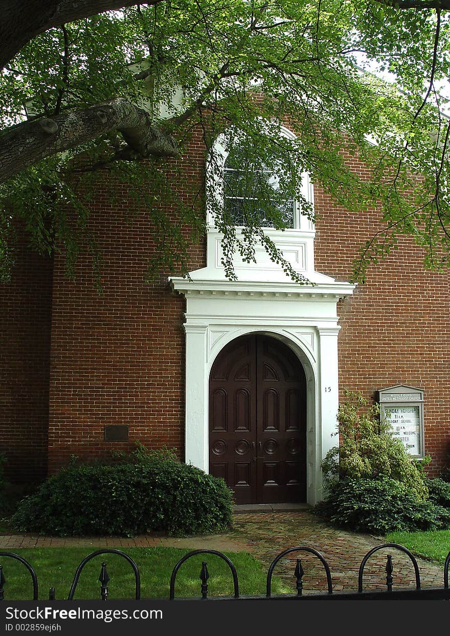 Church entrance surrounded by beautiful green leaves to this small brick and white church. Church entrance surrounded by beautiful green leaves to this small brick and white church.