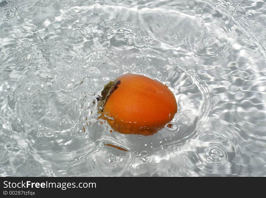 Kaki fruit splashing into water