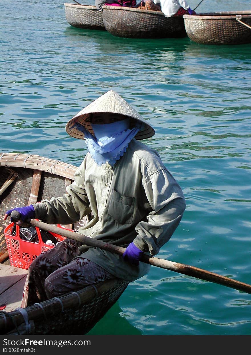 A totaly covered vietnamese woman in a traditional boat. A totaly covered vietnamese woman in a traditional boat