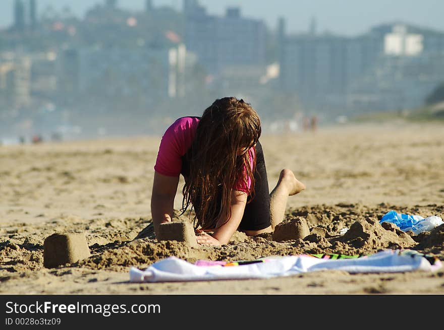 Little girl building sand castles on a beach. Little girl building sand castles on a beach