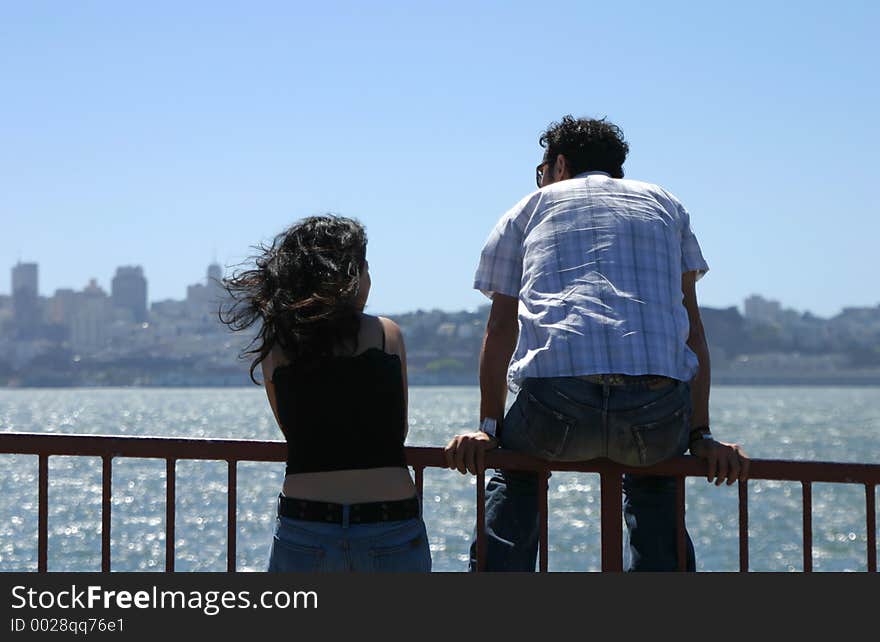 A young couple enjoys a sunny day at the shore of the bay. A young couple enjoys a sunny day at the shore of the bay.