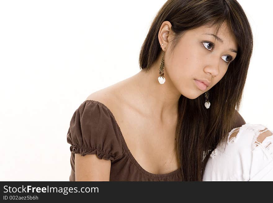 A pretty young teenage woman in a brown top sits and thinks. A pretty young teenage woman in a brown top sits and thinks