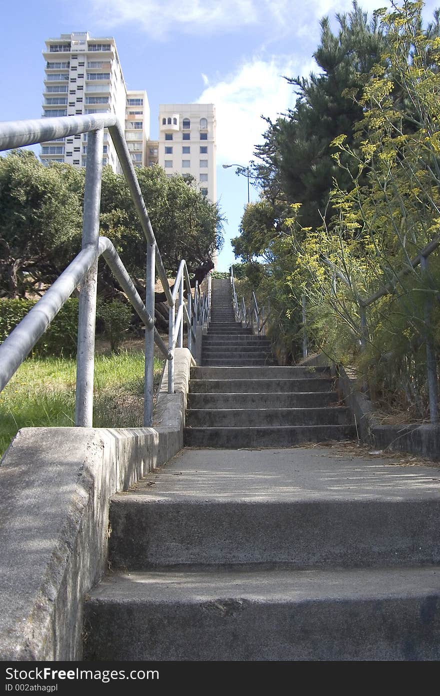 A long stairway leading up a hill to a group of city apartments. A long stairway leading up a hill to a group of city apartments.