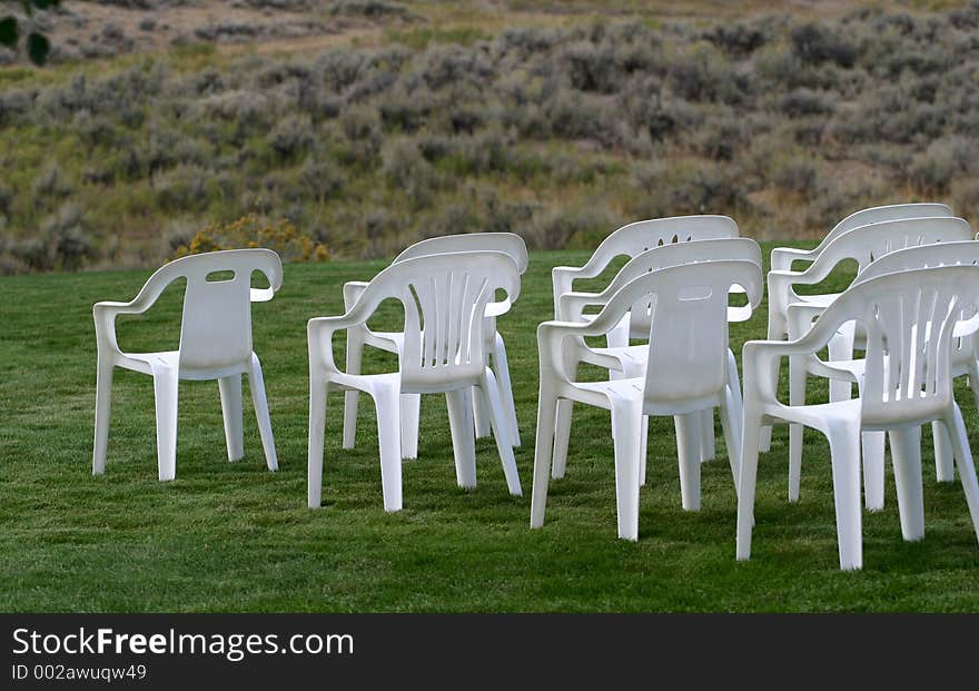 Rows of empty white plastic chairs outside on a green lawn as seen from the back. Corporate applications, communications, business events and more. Rows of empty white plastic chairs outside on a green lawn as seen from the back. Corporate applications, communications, business events and more.