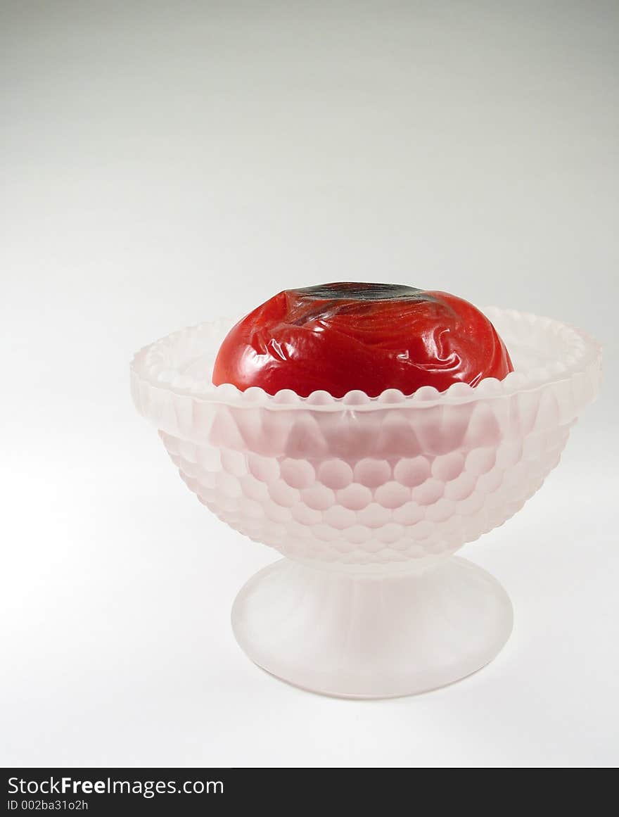 A side view of a rotten tomato in a white frosted-glass sherbet dish. A side view of a rotten tomato in a white frosted-glass sherbet dish.