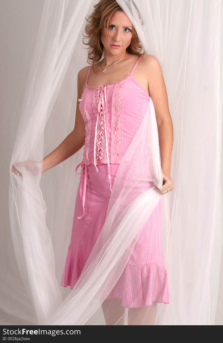 Woman in pink dress posing with white netting. Woman in pink dress posing with white netting