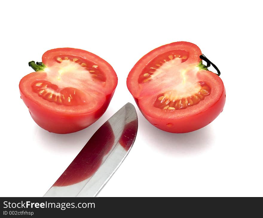 Two half of tomato with knife over the white. Two half of tomato with knife over the white