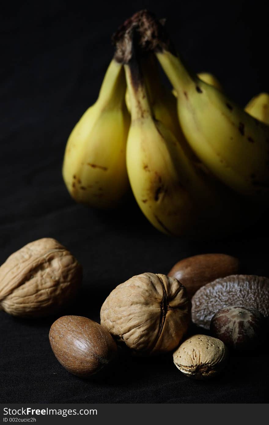 Banana and nuts on black background and with shadows