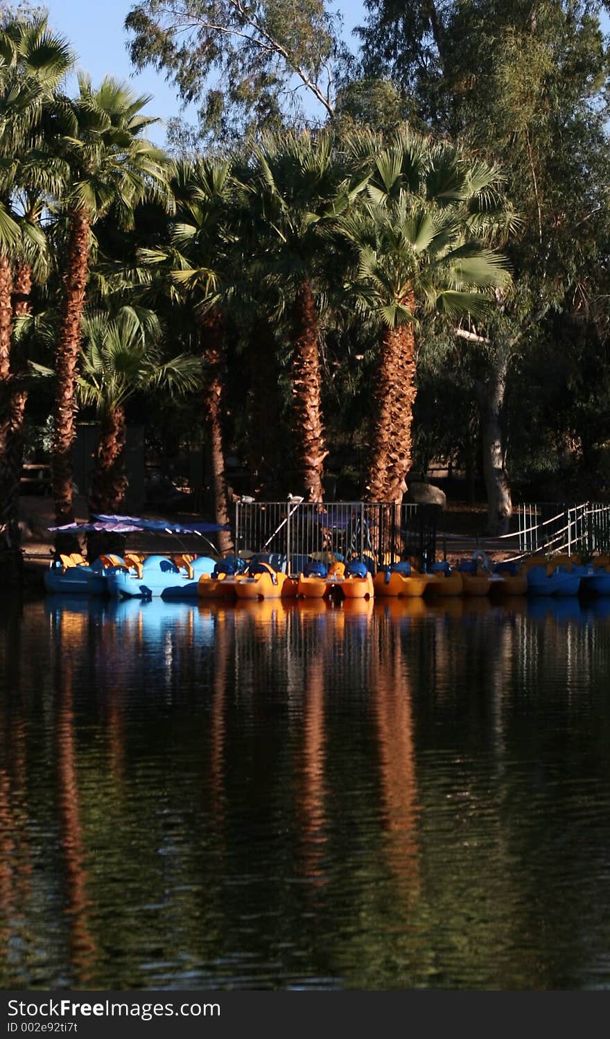 Blue and yellow paddle boats at the dock reflected in lake. Blue and yellow paddle boats at the dock reflected in lake