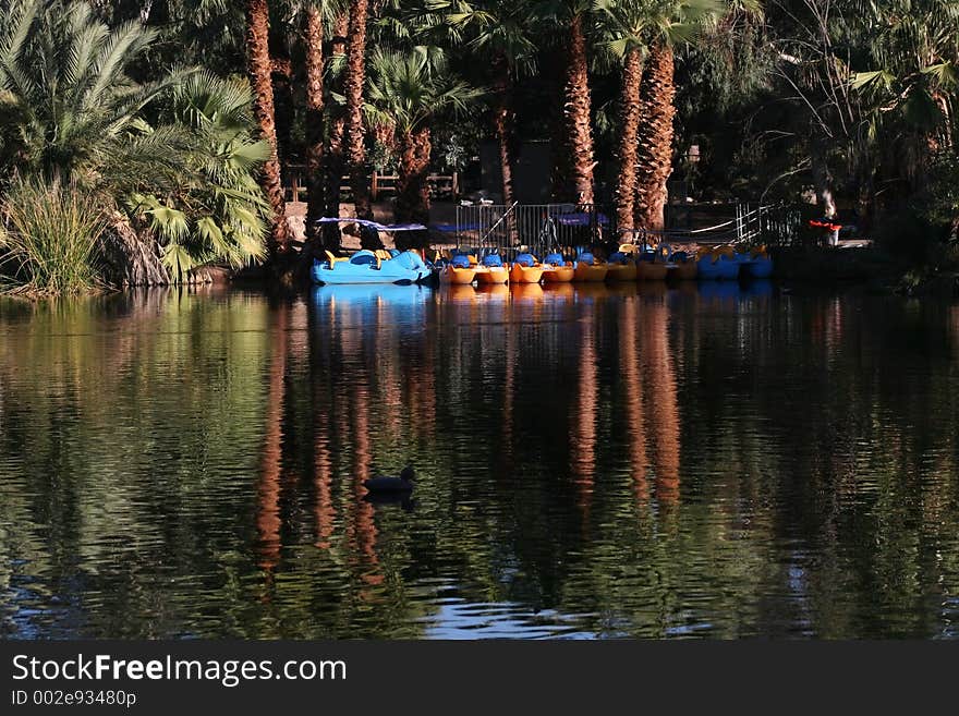 Blue and yellow paddle boats at the dock reflected in lake. Blue and yellow paddle boats at the dock reflected in lake